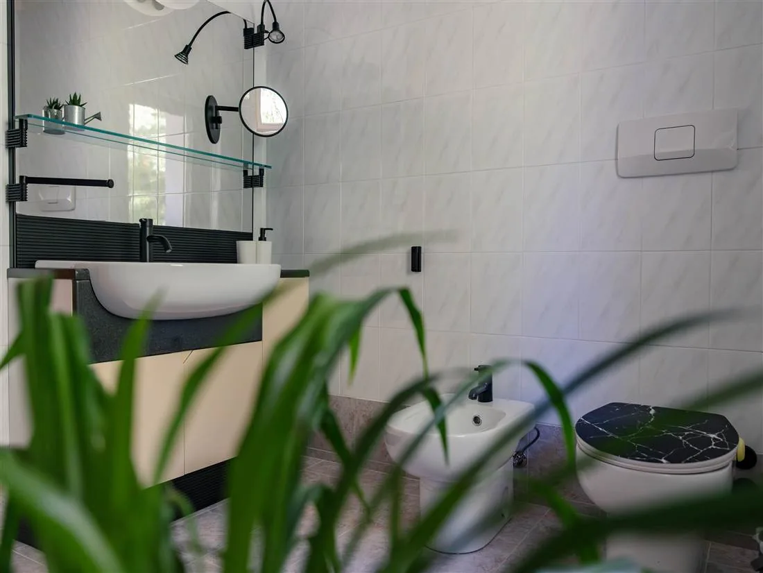 Il secondo bagno con grande specchio, bidet e dettagli neri
