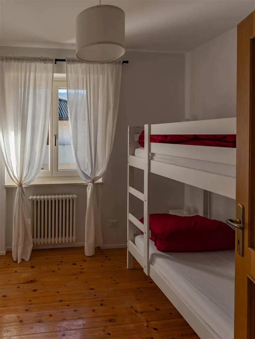 La seconda cameretta con letto a castello, piumoni rossi e pavimento in legno