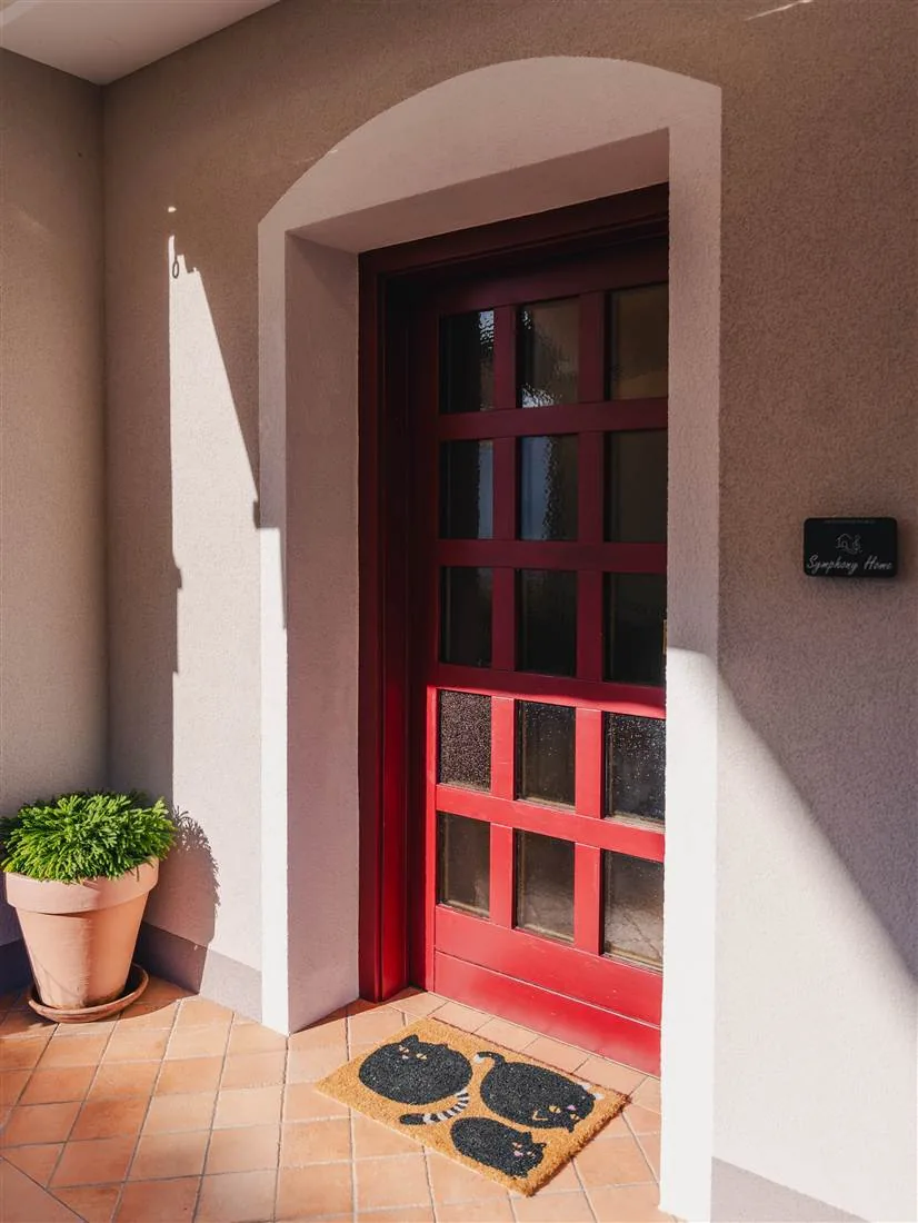 L'ingresso di Symphony Home: porta rossa sotto l'arco, targhetta con il nome e zerbino con i gatti