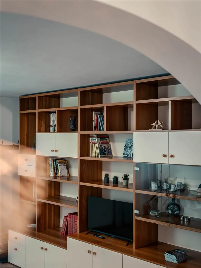 La grande libreria in legno sotto l'arco del soggiorno, nella luce del tramonto