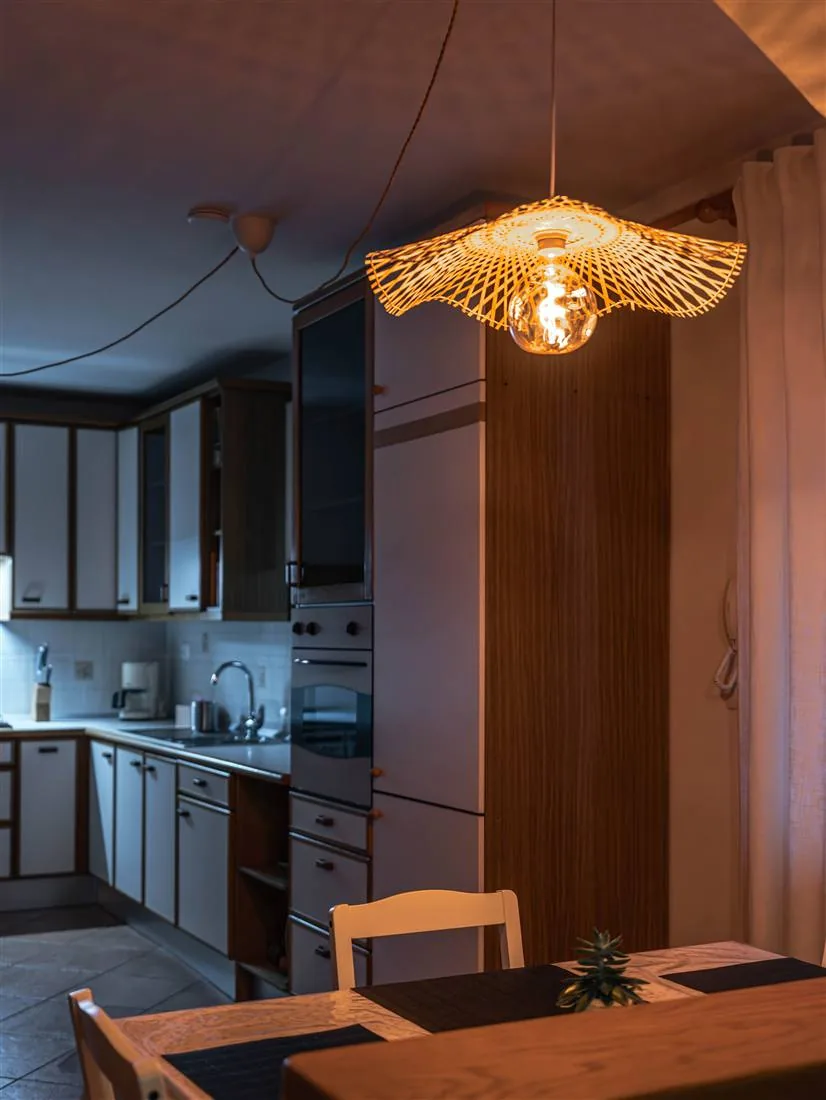La lampada in rattan accesa sopra il tavolo da pranzo, la sera