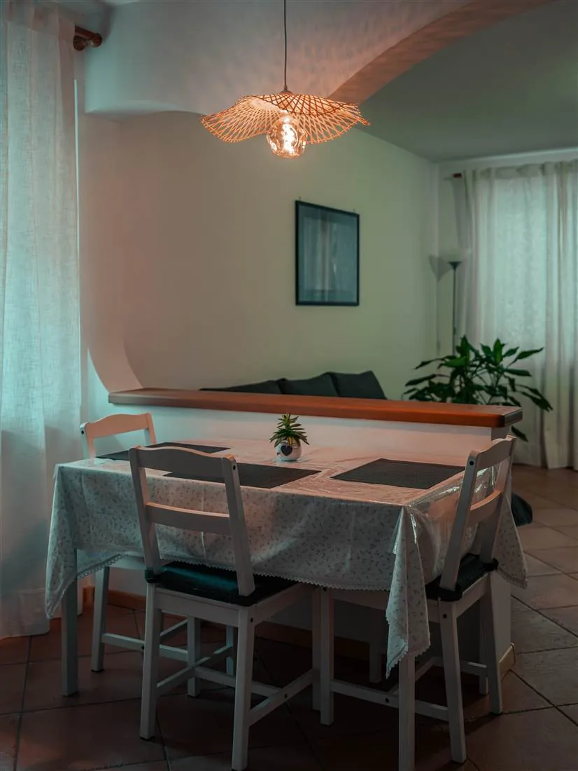 Il tavolo da pranzo apparecchiato sotto la lampada in rattan accesa